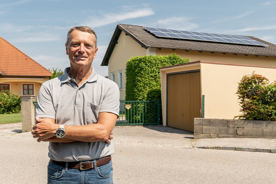 Mann vor Haus mit PV-Anlage