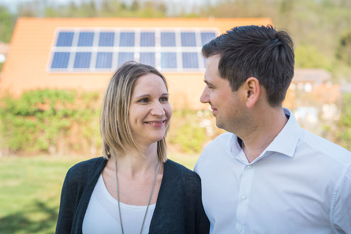 Paar vor Haus mit PV-Anlage